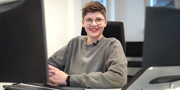 Junger Mann mit hellbraunen Haaren, trägt eine Brille und einen hellgrauen Pullover.