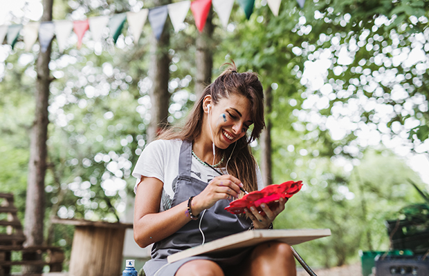 Eine Frau trägt Kopfhörer und malt auf eine Leinwand.