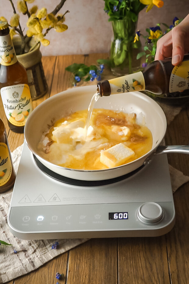 Krombacher Radler läuft in eine Pfanne mit Butter und Zucker auf einer Kochstation.