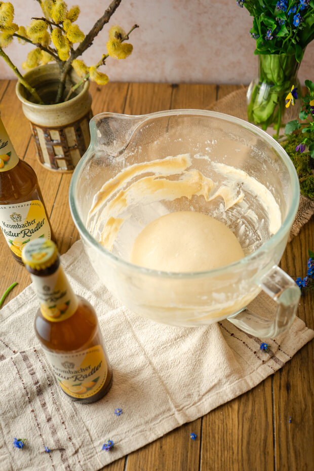 Eine weiße Schüssel mit Teig, darunter ein weißes Tuch.