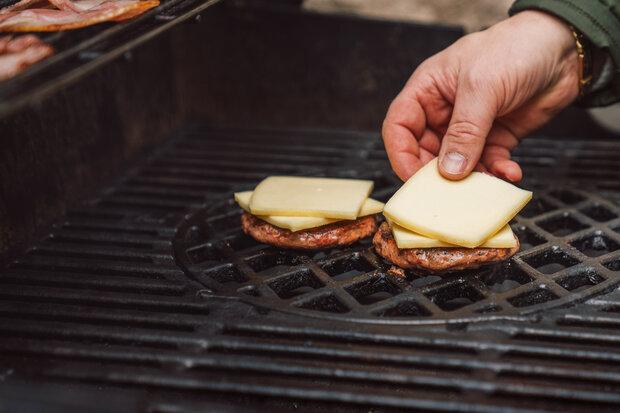 Auf die Patties auf dem Grill wird Käse draufgelegt.