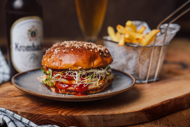 Der Bier Burger, angerichtet mit Pommes auf einer Holzplatte.
