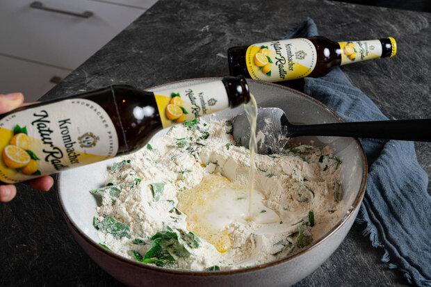 Krombacher Natur Radler wird in die Schüssel mit Mehl und Rucola geschüttet.
