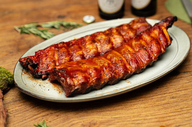 Zwei Biermarinierte Rippchen liegen längs auf einem Teller.