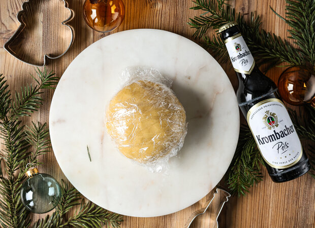 Der runde Teig liegt in Frischhaltefolie eingepackt auf dem Teller.