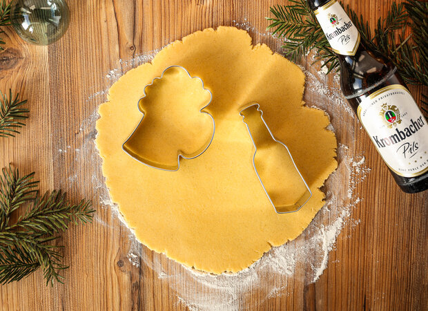 Auf dem ausgerollten Teig liegen Ausstechformen mit Biermotiven.