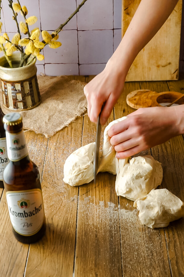  Eine Hand zieht den Teig in mehrere Teile.