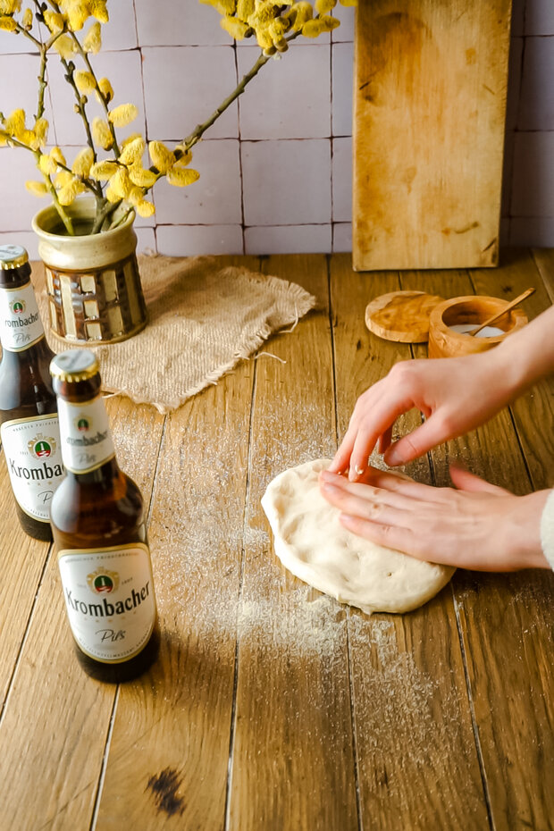 Zwei Hände drücken die Teigteile platt