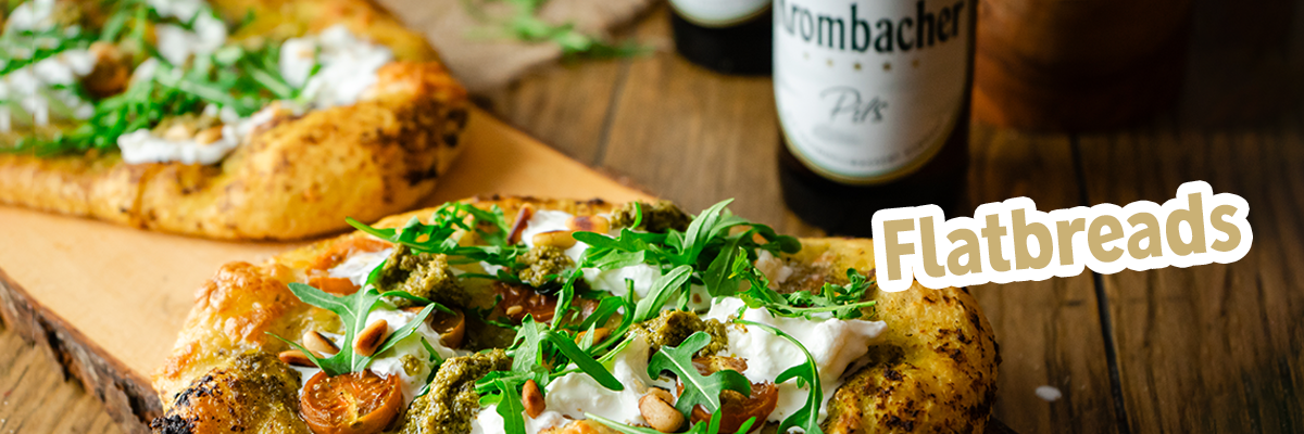 Flatbreads mit Tomaten und Rucola auf einer Hölzernen Platte.