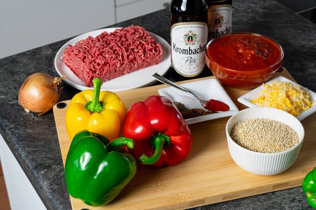 Paprikas und Gewürze liegen auf einem Holzbrett.