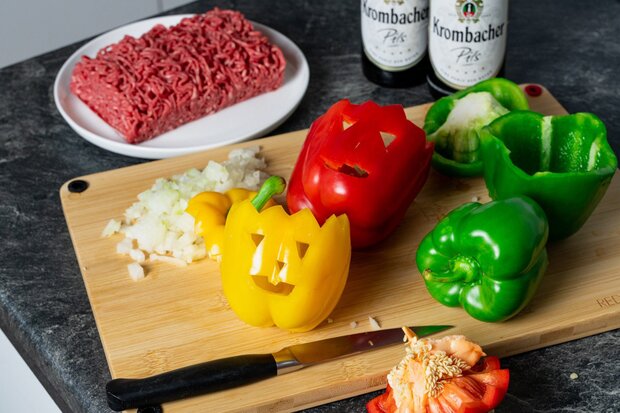 Im halloweenlook geschnittene Paprikas liegen auf einem Holzbrett.