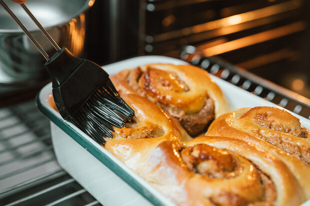 Die Hefeschnecken werden in einer weiß türkisen Backform überstrichen.