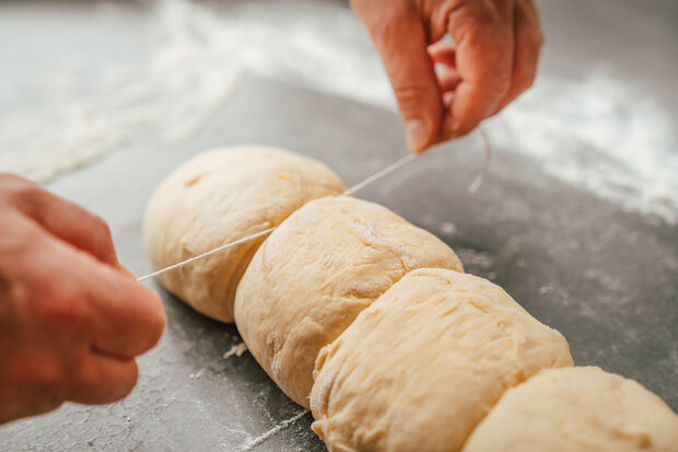 Der Hefeteig wird mit einem Seil in kleine Schnecken geteilt.