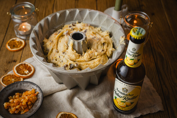 Der Teig steht in einer Kuchenform auf einer Holzplatte.