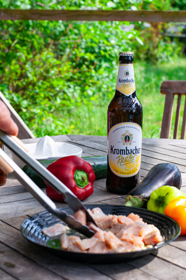 Der Lachs wird mit einer Grillzange in eine Marinade eingelegt.