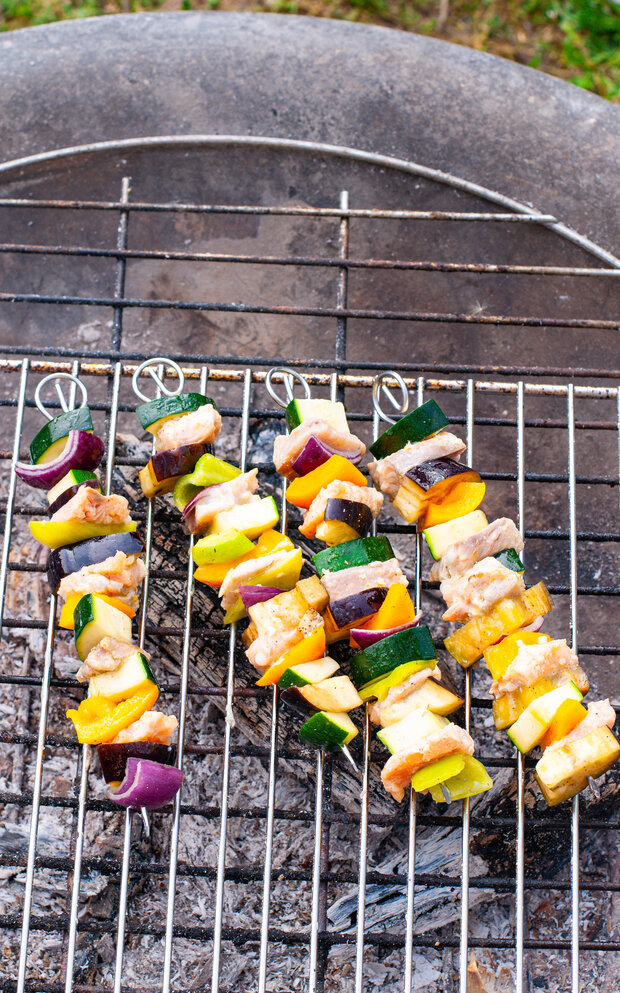 Mehrere Lachsspieße liegen auf dem Grill.