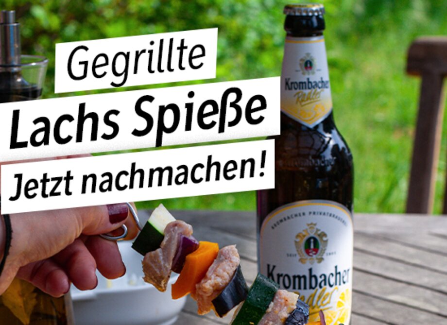 Ein selbstgemachter gegrillter Lachsspieß mit einem Krombacher Radler im Hintergrund.