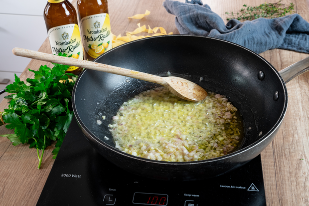 Zwiebeln werden auf einer Pfanne angeschwitzt.