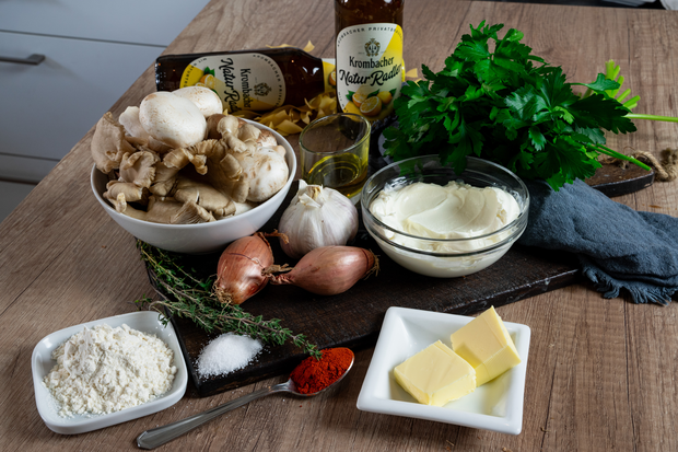 Sämtliche Zutaten für die Mushrooms a la Stroganoff auf einer Holzplatte.