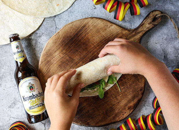 Der Belegte Wrap wird auf einem Holzbrett eingerollt.