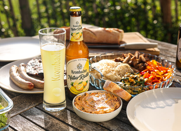 Selbstgemachte Tomatenkräuterbutter auf einem Holztisch mit Grillgut.