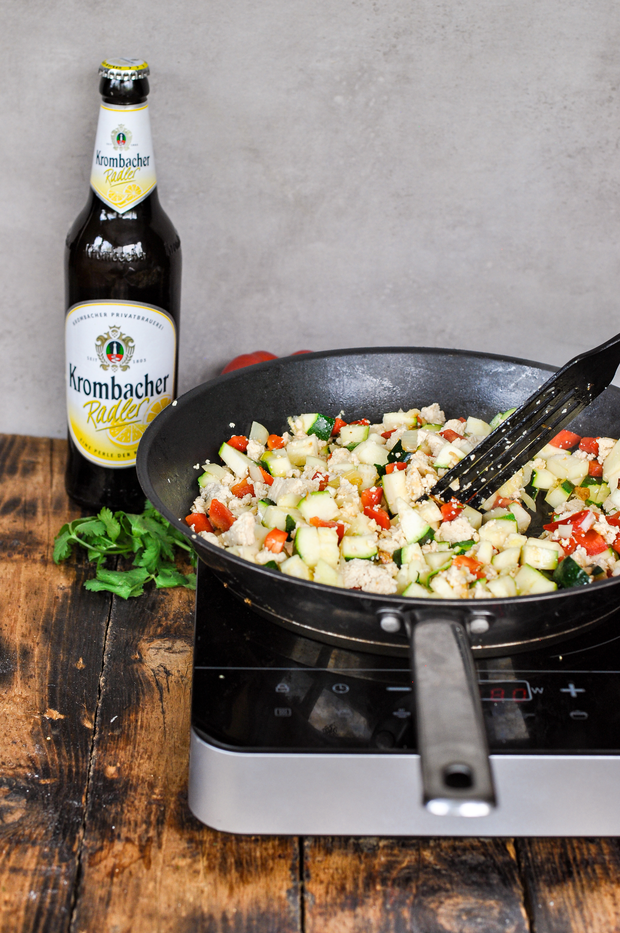 Zur Pfanne wird geschnittenes Gemüse hinzugegeben.