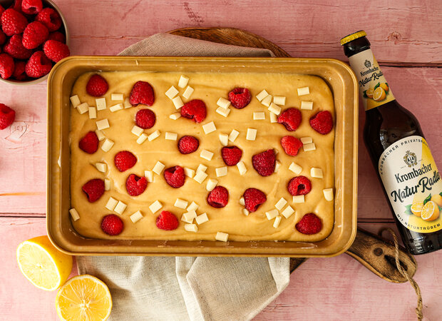 Teig in einer Backform mit weißer Schokolade und Himbeeren.