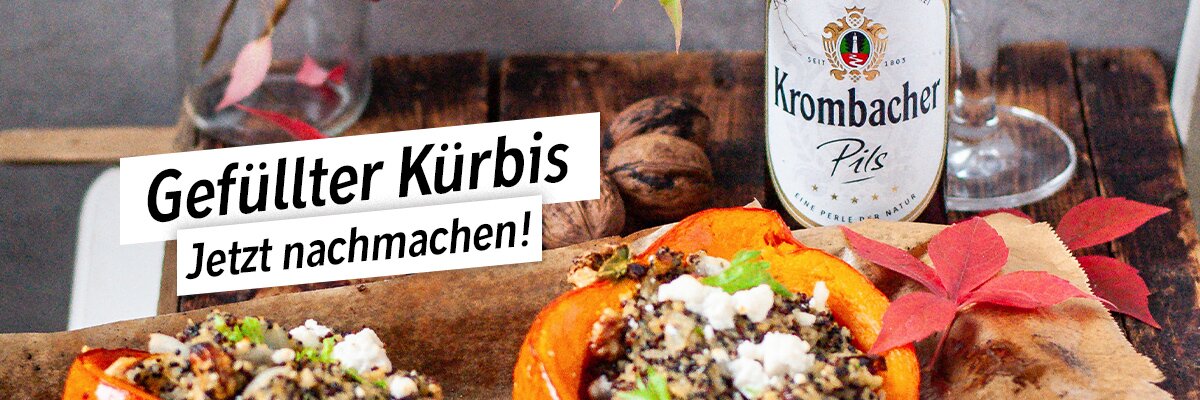 Ein gefüllter Kürbis auf einem Holzbrett, umgeben von Walnüssen und herbstlichen Blättern.