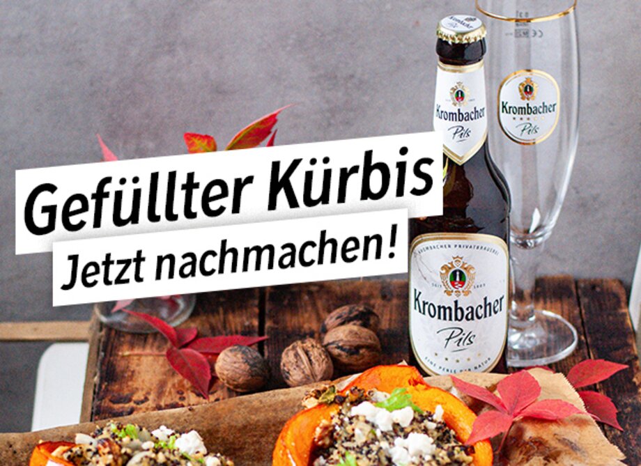 Ein gefüllter Kürbis auf einem Holzbrett, umgeben von Walnüssen und herbstlichen Blättern.