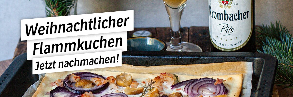 Ein Flammkuchen mit Zwiebeln und Speck auf einem Blech, umgeben von Tannenzweigen. Im Hintergrund stehen ein Krönbacher Pils Bier und ein Glas Bier.