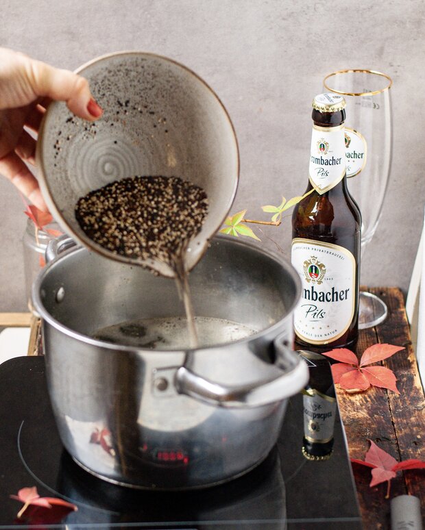 Schale mit Quinoa wird über kochender Gemüsebrühe ausgeschüttet.