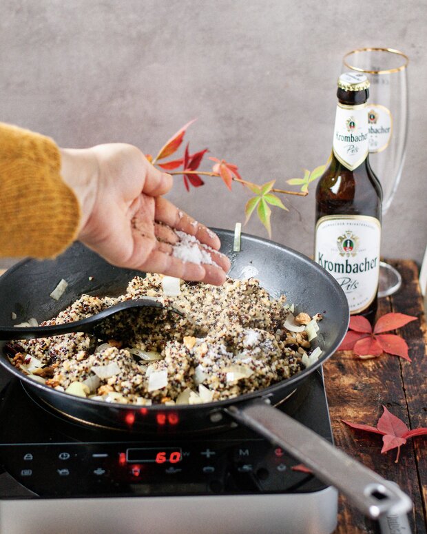 Der Pfanne wird der gekochte Quinoa aus der Gemüsebrühe hinzugefügt.
