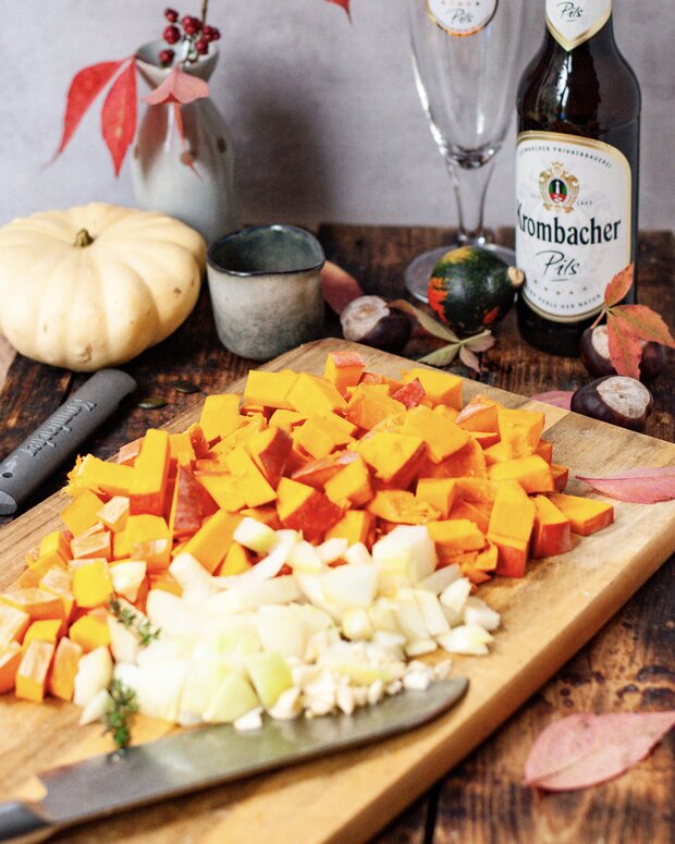 Geschnittene Kürbiswürfel auf einem Holzbrett.