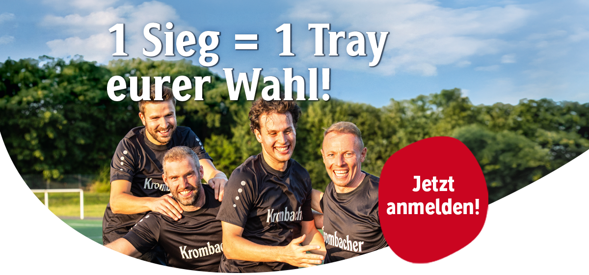 Vier Männer in schwarzen Krombacher-Trikots lachen und umarmen sich auf einem Fußballfeld im Freien.
