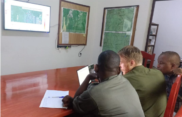 Drei Männer sitzen vor einem Laptop und analysieren etwas.