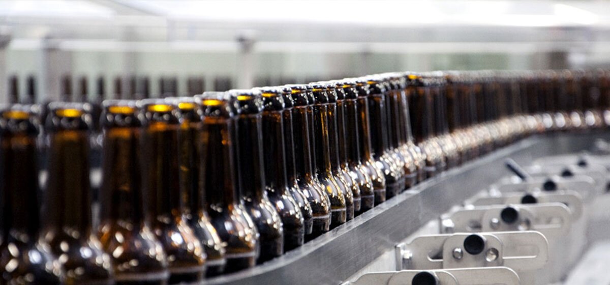 Fließbandanlage in einer modernen Fabrikhalle mit zahlreichen Förderbändern und Abfüllstationen.