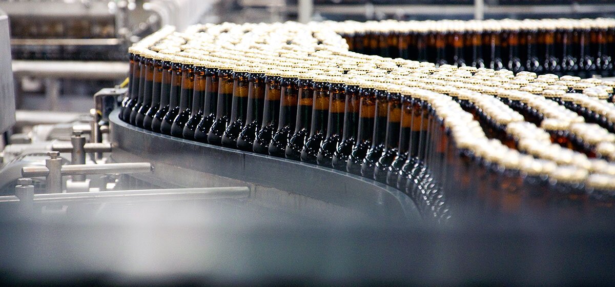 Fließbandanlage in einer modernen Fabrikhalle mit zahlreichen Förderbändern und Abfüllstationen.