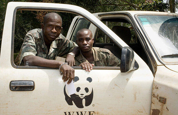 Zwei Männer in Militäruniform lehnen aus dem offenen Fenster eines Geländewagens mit WWF-Logo.