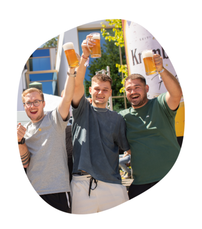Drei Männer heben Biergläser zum Anstoßen beim Krombacher Sommerfest im Freien