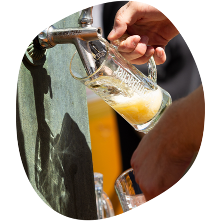 Hand füllt ein Bierglas an dem Zapfhahn des Krombacher Bierbrunnens mit schäumendem Bier beim Sommerfest