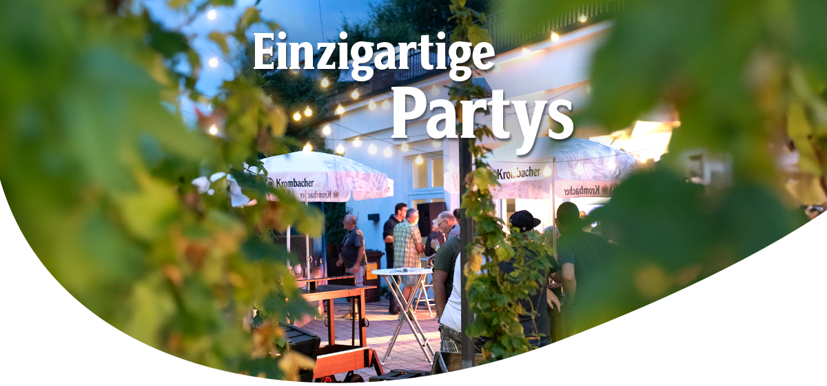 Abendliche Szene mit Menschen unter Lichterketten und Krombacher-Sonnenschirmen im Außenbereich der Krombacher Erlebniswelt. Headline: Einzigartige Partys