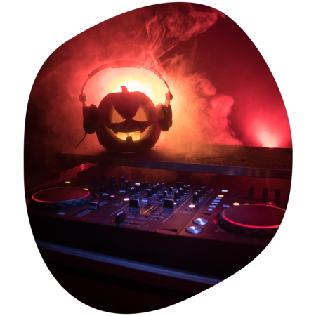 Leuchtender Halloween-Kürbis mit Kopfhörern auf DJ-Pult, rotes Bühnenlicht und Nebel im Hintergrund
