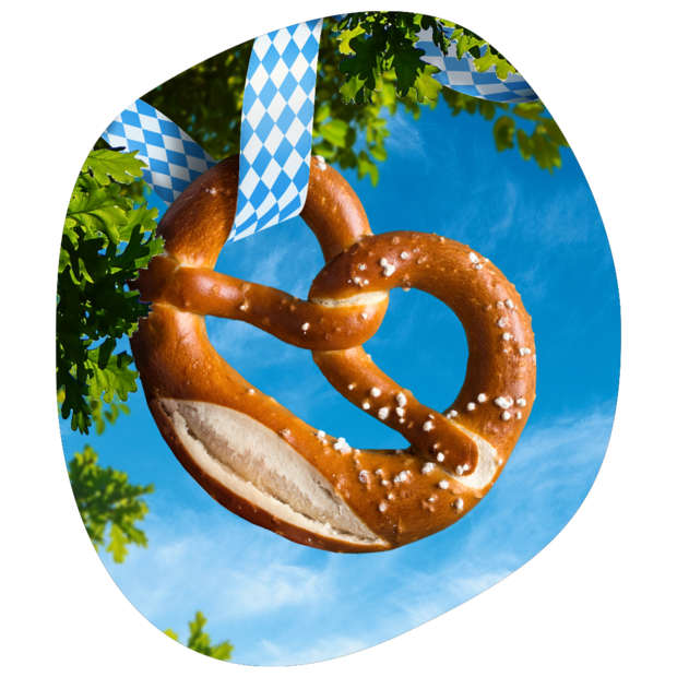 Große Brezel mit grobem Salz, aufgehängt an blau-weiß kariertem Band vor blauem Himmel und grünen Blättern.