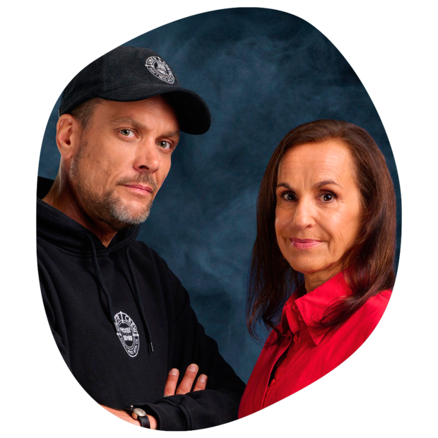 Zwei Personen vor blauem Hintergrund, eine trägt schwarze Kapuzenjacke und schwarze Kappe mit weißem Logo, die andere rote Bluse.