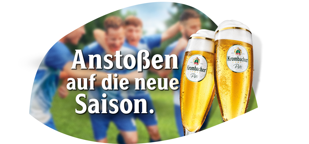 Zwei gefüllte Krombacher Pils Biergläser stoßen an vor verschwommenen Fußballspielern auf dem Spielfeld mit Text 'Anstoßen auf die neue Saison.'