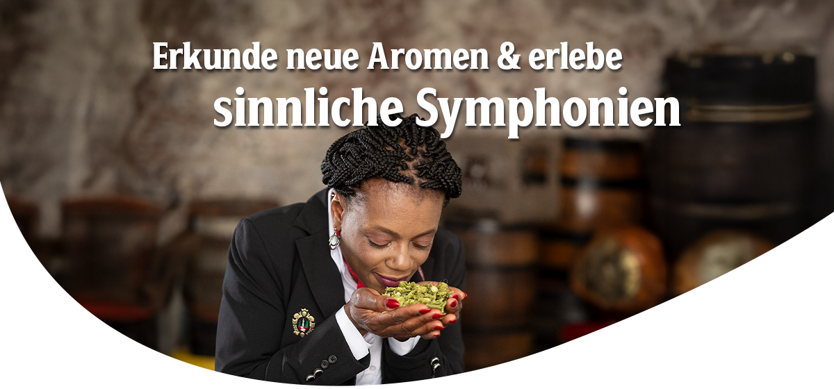 Frau mit geflochtenem schwarzen Haar und schwarzem Blazer hält frischen Hopfen in den Händen und riecht daran. Headline: Erkunde neue Aromen & erlebe sinnliche Symphonien.