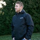 Mann trägt schwarze Krombacher Regenjacke mit Kapuze, steht vor grünen Büschen.