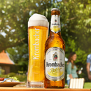 Ein frisch gefüllter Star Cup neben einer kalten Flasche Krombacher Radler im grünen Garten.