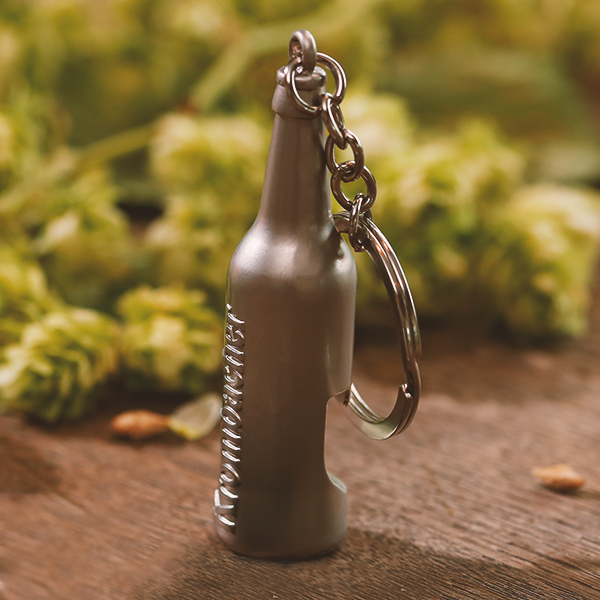 Metall-Schlüsselanhänger in Form einer Krombacher Pils Flasche mit integriertem Flaschenöffner.