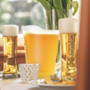 Krombacher Pils im Pitcher und zwei Gläsern auf einem gedeckten Tisch.